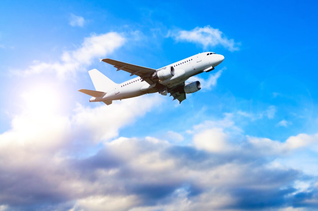 airplane in flight, traveling across a blue sky